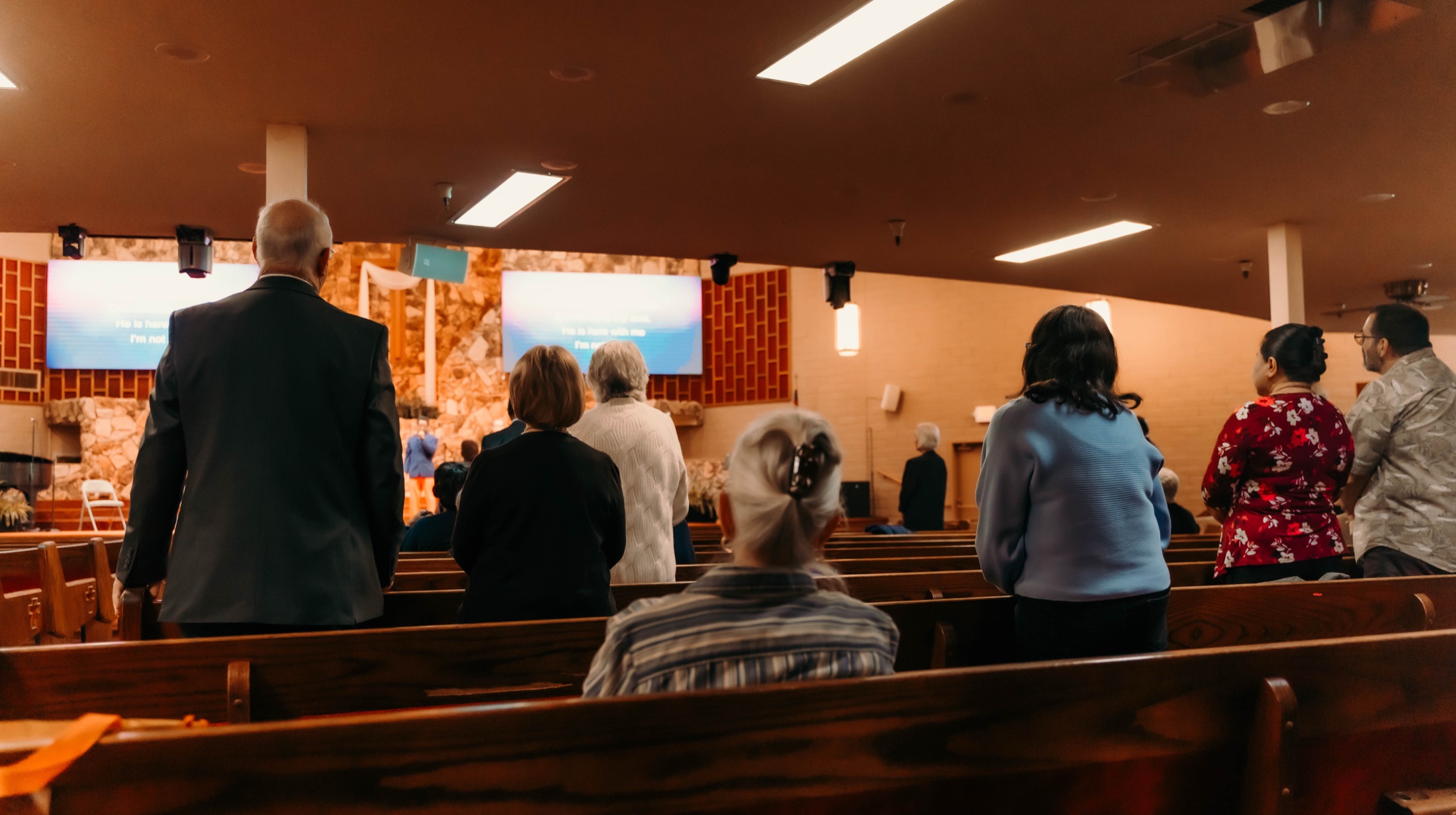 Congregation with hands raised in worship, warm golden stage light